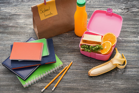 Composition with appetizing food in lunch box and stationery on wooden backgroundの写真素材