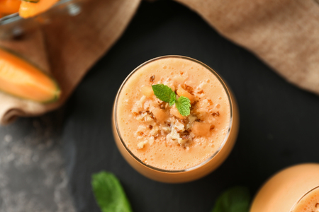 Glass of tasty melon smoothie on tableの写真素材