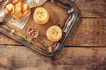 Glasses with tasty melon smoothie and peanuts on trayの写真素材