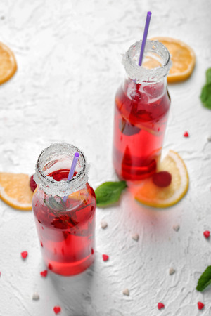 Bottles of fresh raspberry lemonade on white tableの写真素材