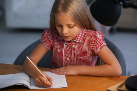 Little girl doing homework at home in eveningの写真素材