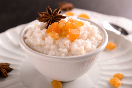 Delicious rice pudding with dried fruits and anise in bowl on plateの写真素材