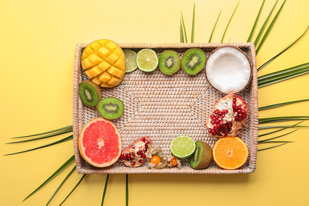 Wicker tray with various delicious fruits on color backgroundの写真素材