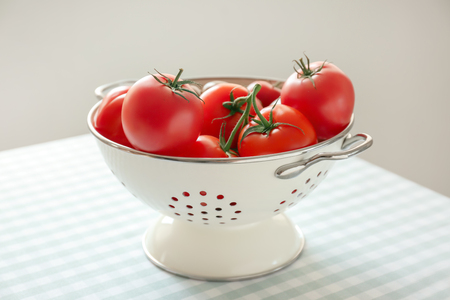 Colander with delicious tomatoes on tableの写真素材