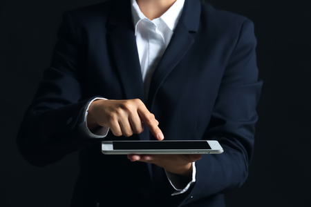 Businesswoman with tablet PC on dark backgroundの写真素材