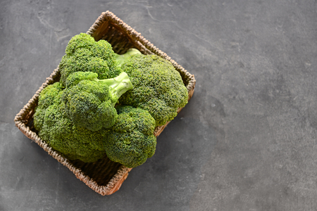 Basket with fresh green broccoli on grey tableの写真素材