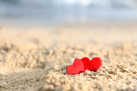Small red hearts on beach sandの写真素材