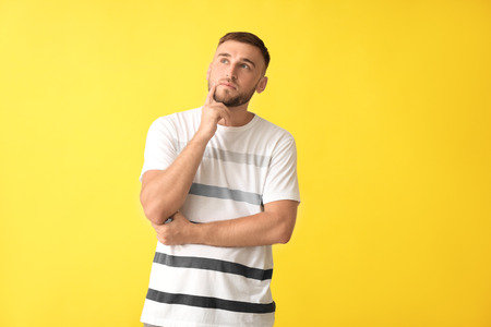 Thoughtful young man on color background