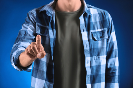 Young man using virtual screen on color backgroundの写真素材