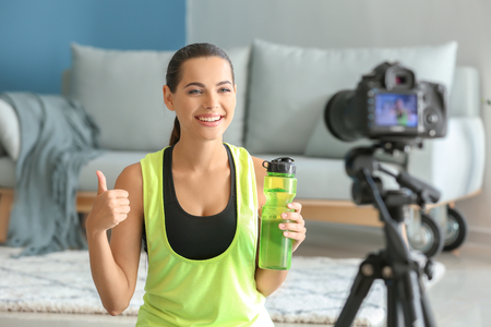 Young female blogger recording sports video at homeの写真素材