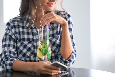 Young woman drinking fresh lemonade at homeの写真素材