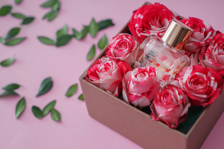 Box with bottle of perfume and roses on color backgroundの写真素材