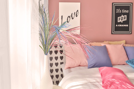 Vase with color tropical leaves on table in interior of modern comfortable bedroom