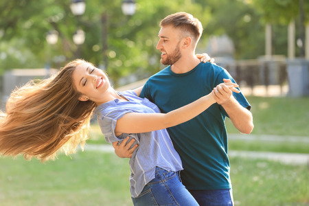 Happy young couple dancing in park