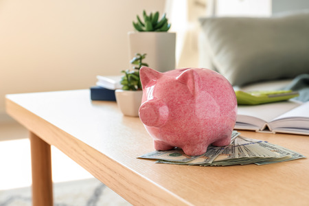 Piggy bank with money on light wooden table indoorsの写真素材