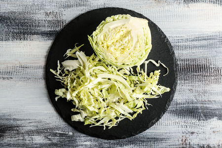 Slate plate with cut cabbage on wooden table