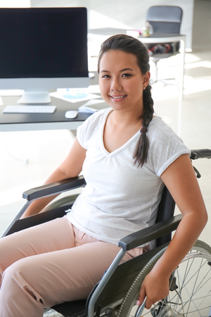 Asian woman in wheelchair in officeの写真素材