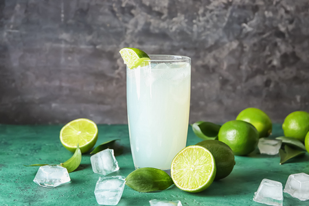 Glass of fresh lime lemonade on color tableの写真素材