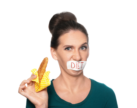 Emotional woman with taped mouth and pastry on white background. Diet conceptの写真素材
