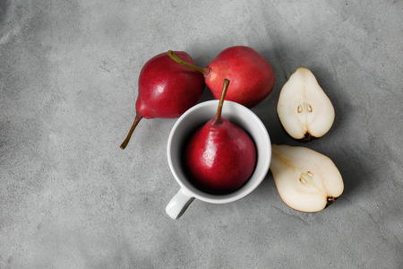 Cup and tasty ripe pears on grey table