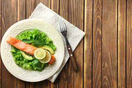 Plate with tasty salmon and fresh salad on wooden tableの写真素材