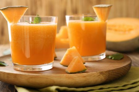 Glasses of tasty melon smoothie on wooden plateの写真素材
