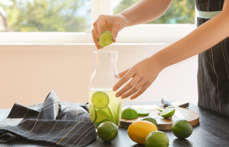Woman preparing lime lemonade at table