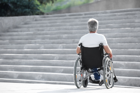 Senior man in wheelchair near stairs outdoorsの写真素材
