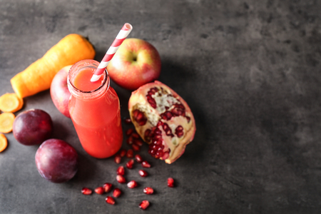 Bottle of tasty red smoothie and ingredients on grey tableの写真素材