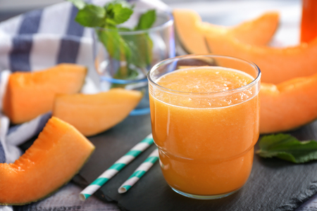 Glass of tasty melon smoothie on tableの写真素材
