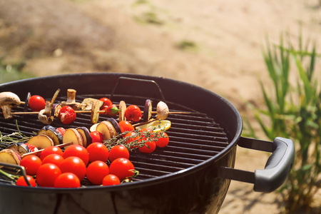 Skewers with vegetables and mushrooms on barbecue grill outdoorsの写真素材