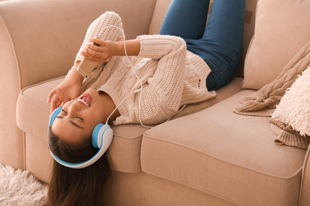 Beautiful young woman listening to music at homeの写真素材