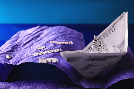 Origami boat with musical notes on paper imitating wavesの写真素材