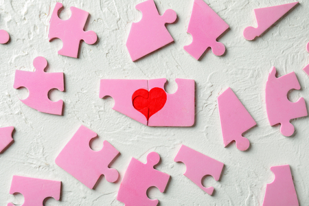 Composition with pink puzzles and heart on light background