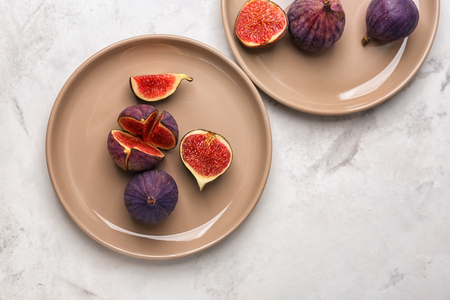 Plates with fresh ripe figs on light tableの写真素材