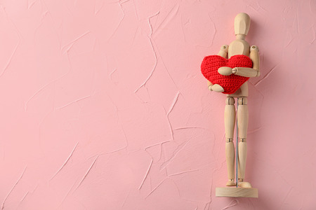 Small wooden mannequin with red heart on color backgroundの写真素材