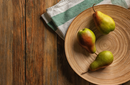 Plate with ripe sweet pears on wooden tableの写真素材