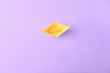 Origami boat on color background