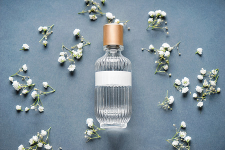 Transparent bottle of perfume with beautiful flowers on grey backgroundの写真素材
