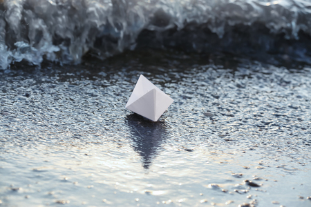 Origami boat on sea shoreの写真素材