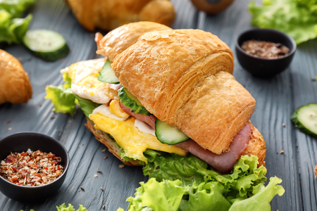 Tasty croissant sandwich with spices on wooden tableの写真素材