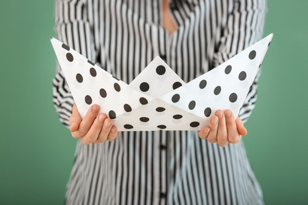 Woman holding origami boat on color backgroundの写真素材