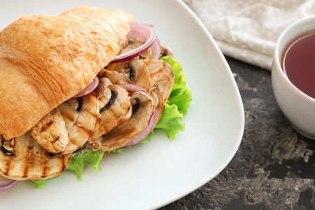 Tasty croissant sandwich with mushrooms on plateの写真素材