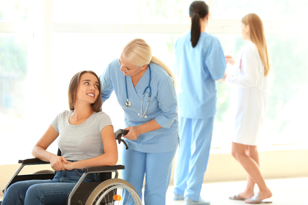 Handicapped young woman with mature female doctor in clinicの写真素材
