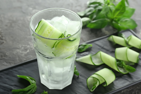 Glass of cucumber infused water with ice on tableの写真素材
