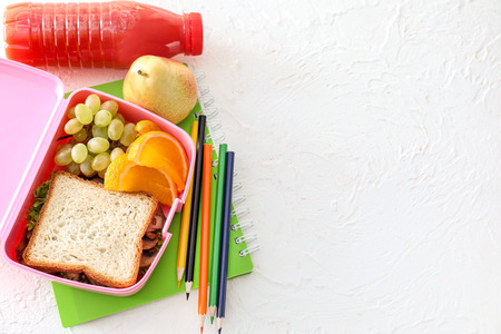 Lunch box with appetizing food and stationery on light tableの写真素材