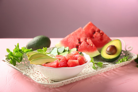 Tasty salad with watermelon, feta and vegetables in bowl on vintage tray