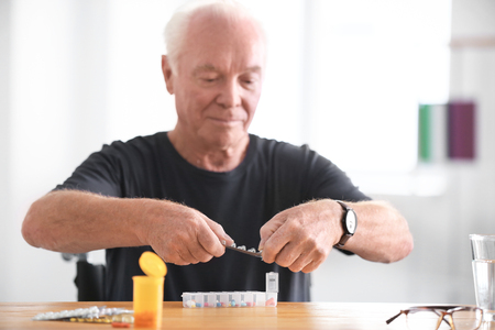 Senior man putting medicine into container at homeの写真素材