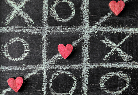 Game of Tic-tac-toe with crossed line and small hearts on blackboardの写真素材