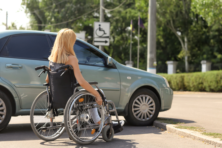 Woman in wheelchair next to her carの写真素材